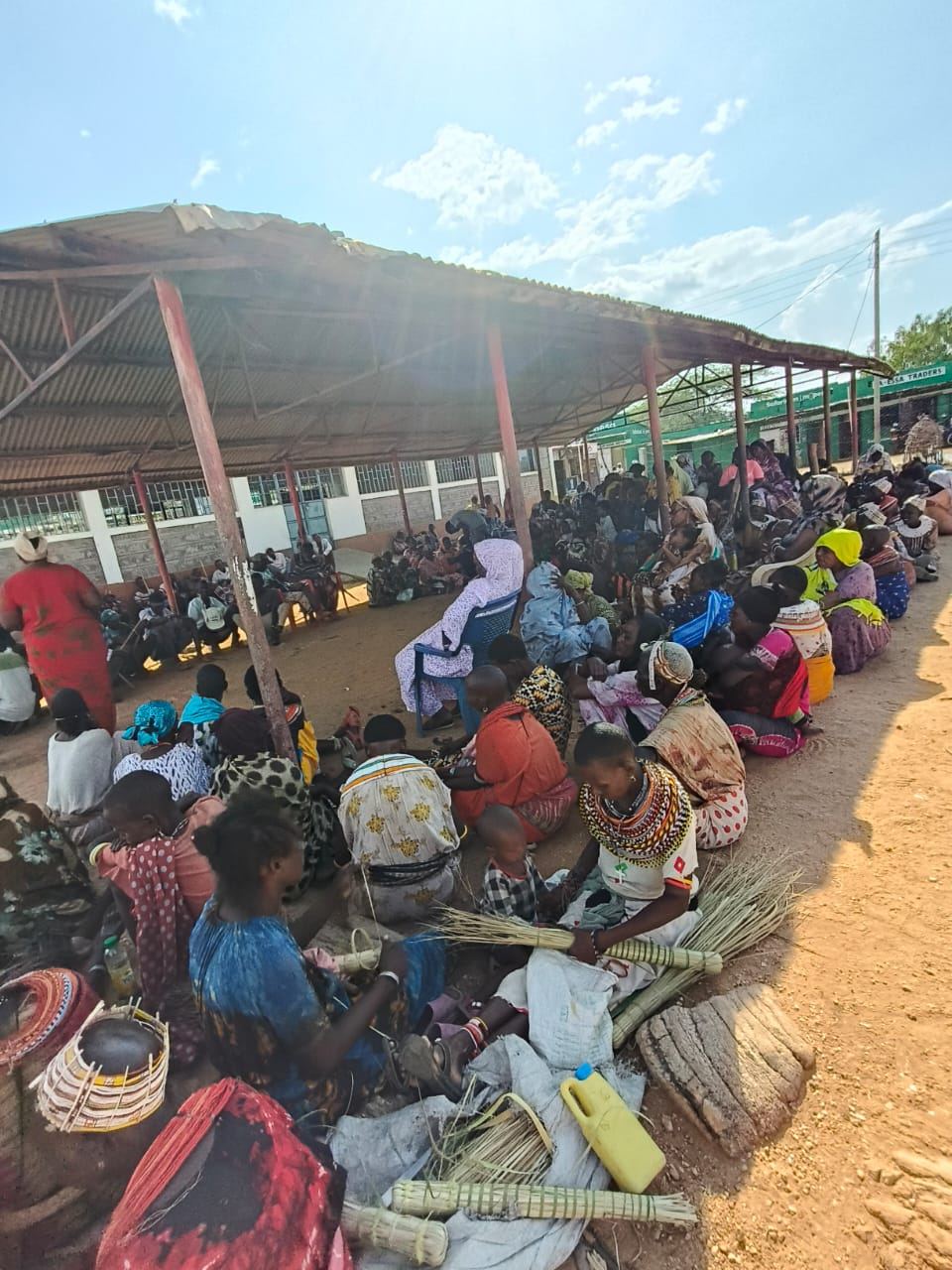 Women weaving baskets together under a shelter in Laisamis